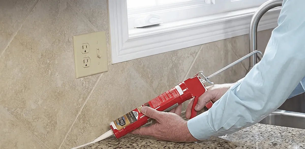 Handyman applying caulk along a kitchen backsplash and countertop seam in Minneapolis, MN