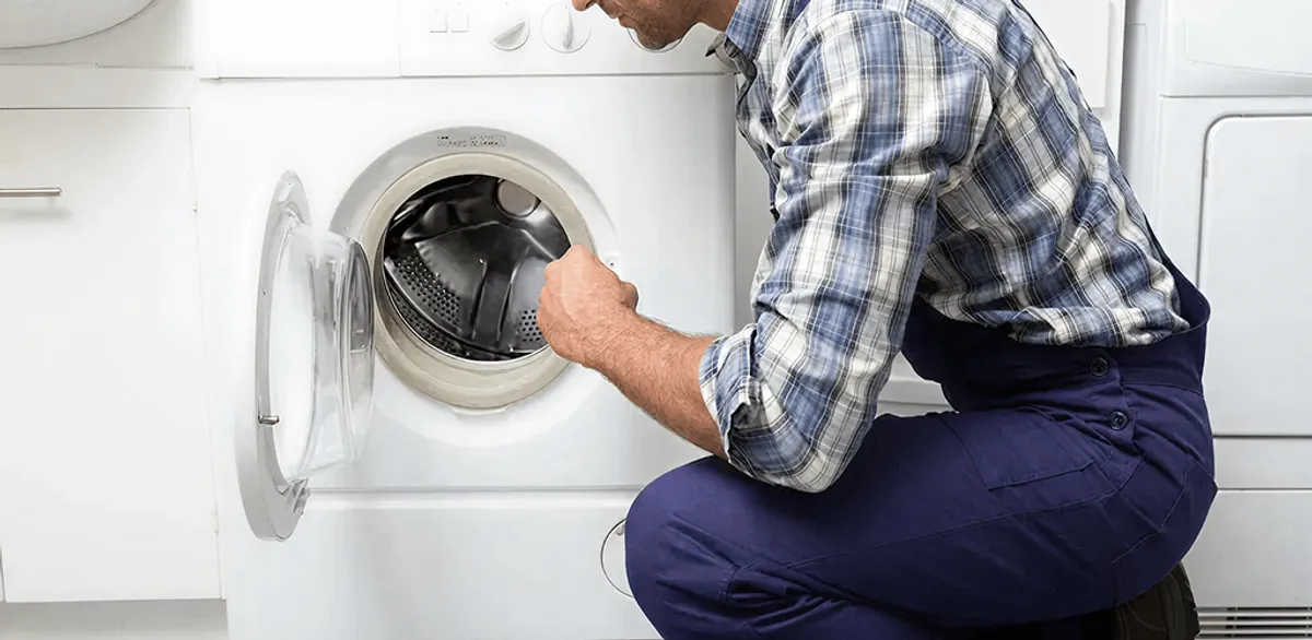 Handyman inspecting a dryer drum and internal parts for repair in Minneapolis, MN