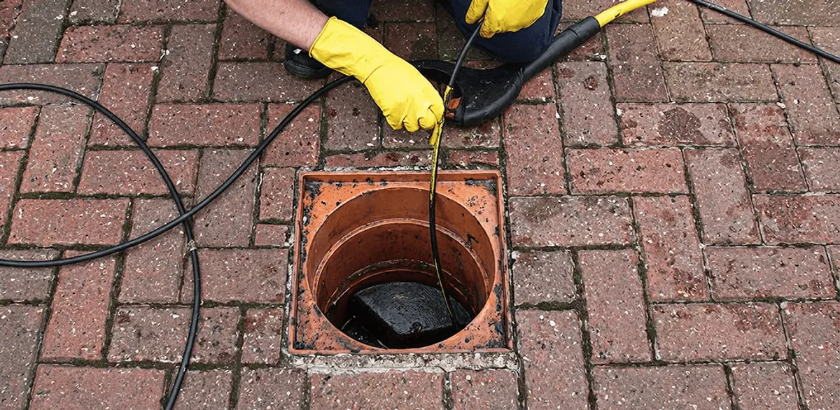 Drain cleaning technician using a drain snake to clear a clogged drain in Minneapolis, MN