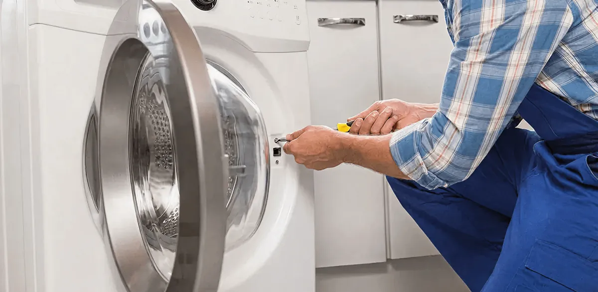 Handyman repairing a clothes dryer and checking electrical connections in Minneapolis, MN