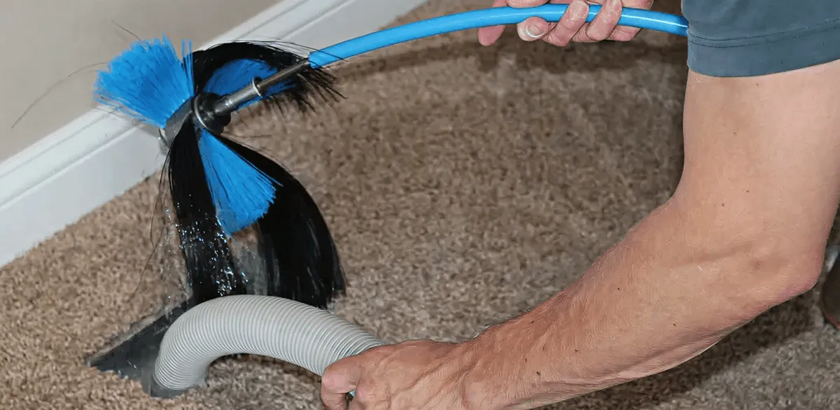 Dryer vent cleaning technician brushing lint from a vent line in Minneapolis, MN