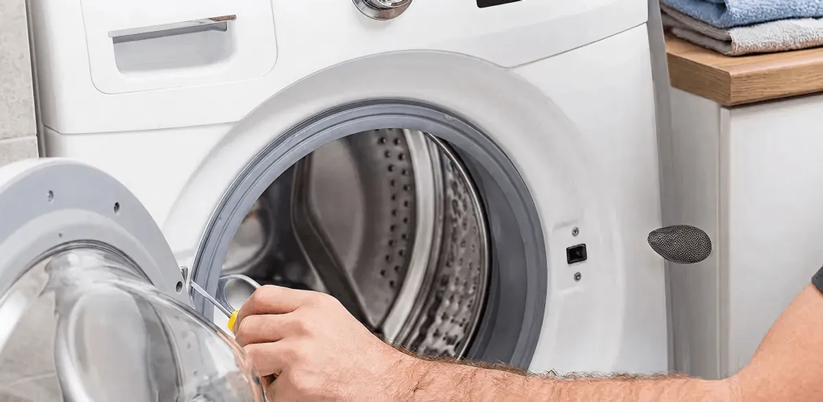 Handyman repairing a front-load washing machine and inspecting the drum in Minneapolis, MN