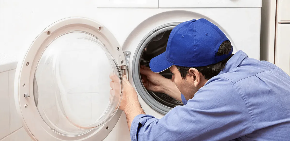 Washing machine repair handyman inspecting a front-load washer drum in Minneapolis, MN